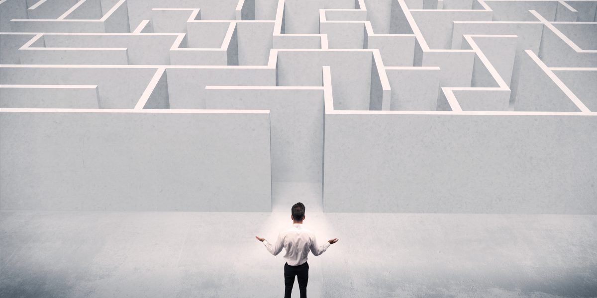 A good looking businessman with briefcase standing in front of white labirynth entrance about to make a decision concept