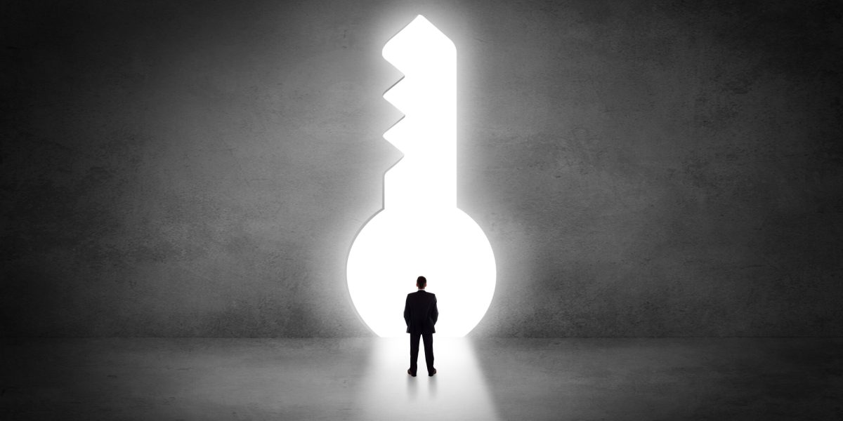 Businessman standing alone in front of a big keyhole
